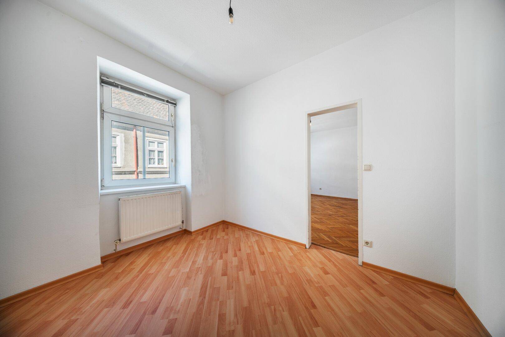 Ruhiges Zimmer mit Laminatboden und einem Fenster, ideal als Schlaf- oder Arbeitszimmer.