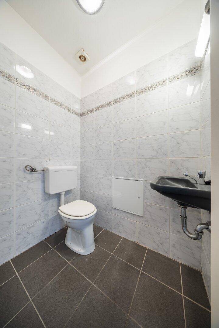 Kleines Gäste-WC mit dunklen Fliesen und einem Waschbecken.