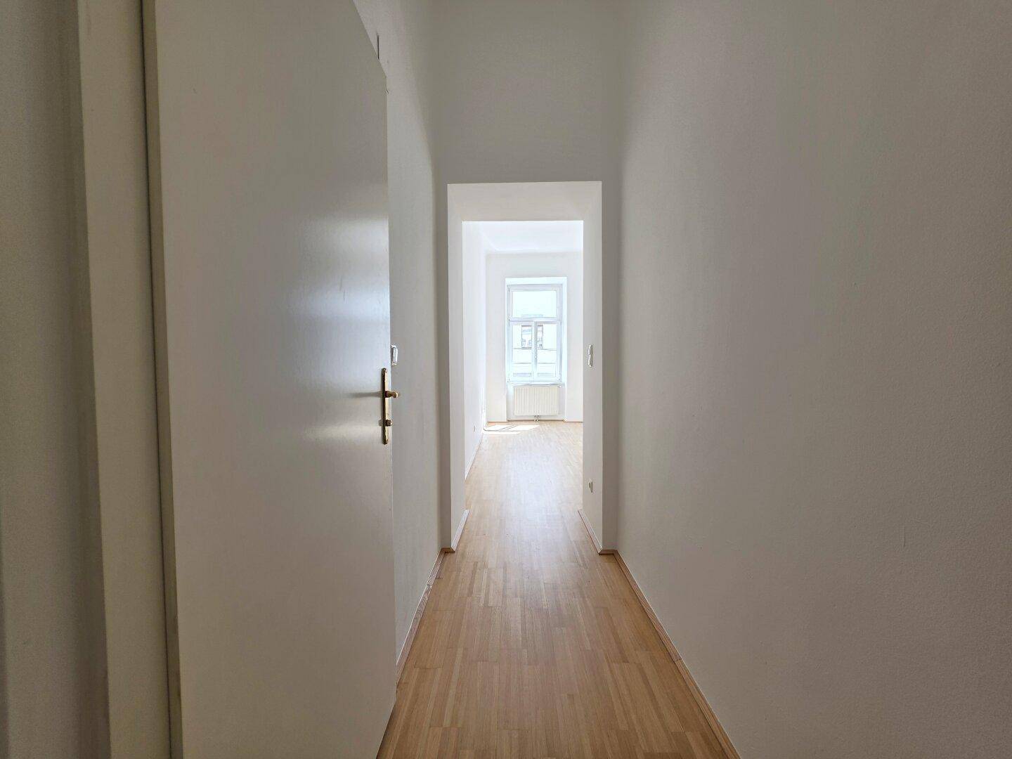 Langer, heller Flur mit Parkettboden, der zu weiteren Räumen der Wohnung führt.