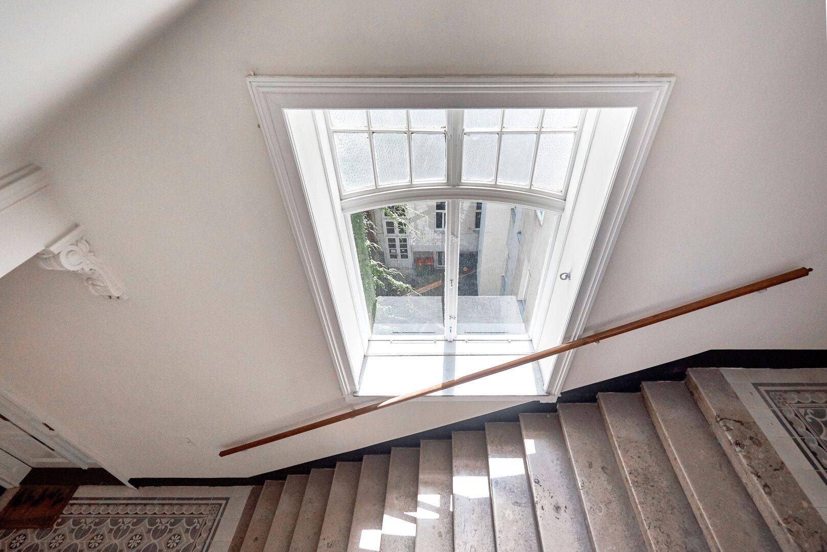 Blick von oben auf ein Treppenhaus mit einem großen Oberlicht, das viel natürliches Licht hereinlässt.