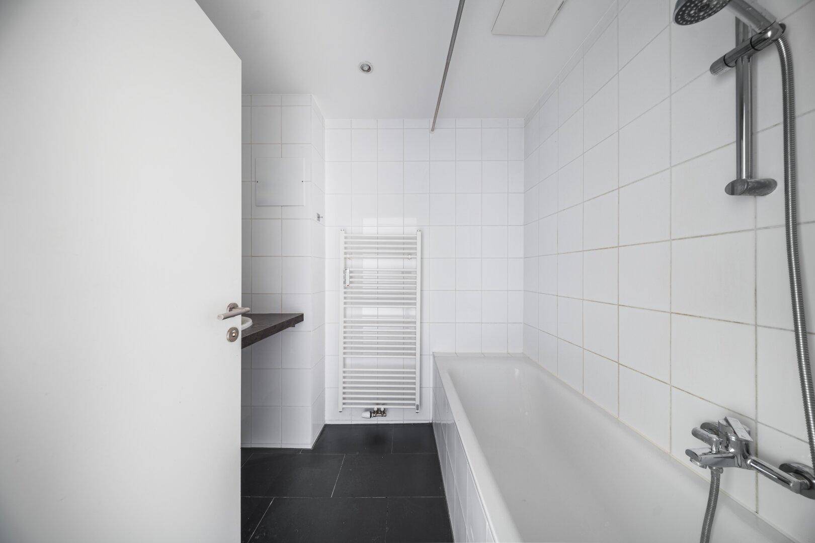 Modernes Badezimmer mit Badewanne, Dusche und weiß gefliesten Wänden.