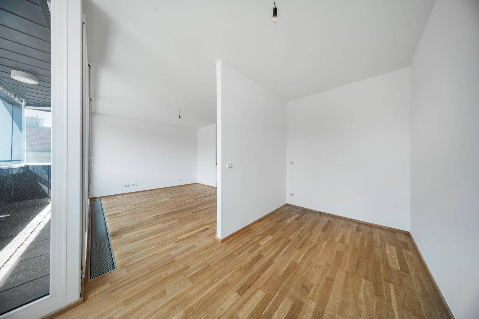Leerer Raum mit Holzboden und weiß gestrichenen Wänden, bereit zur individuellen Gestaltung.