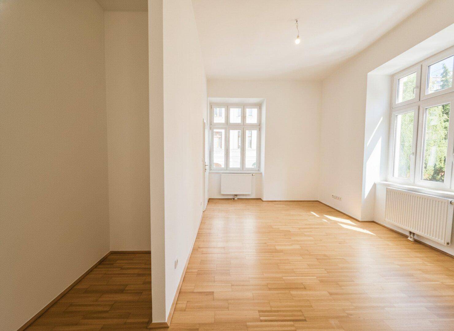 Geräumiges, helles Zimmer mit Parkettboden und großen Fenstern, bereit zur individuellen Gestaltung.