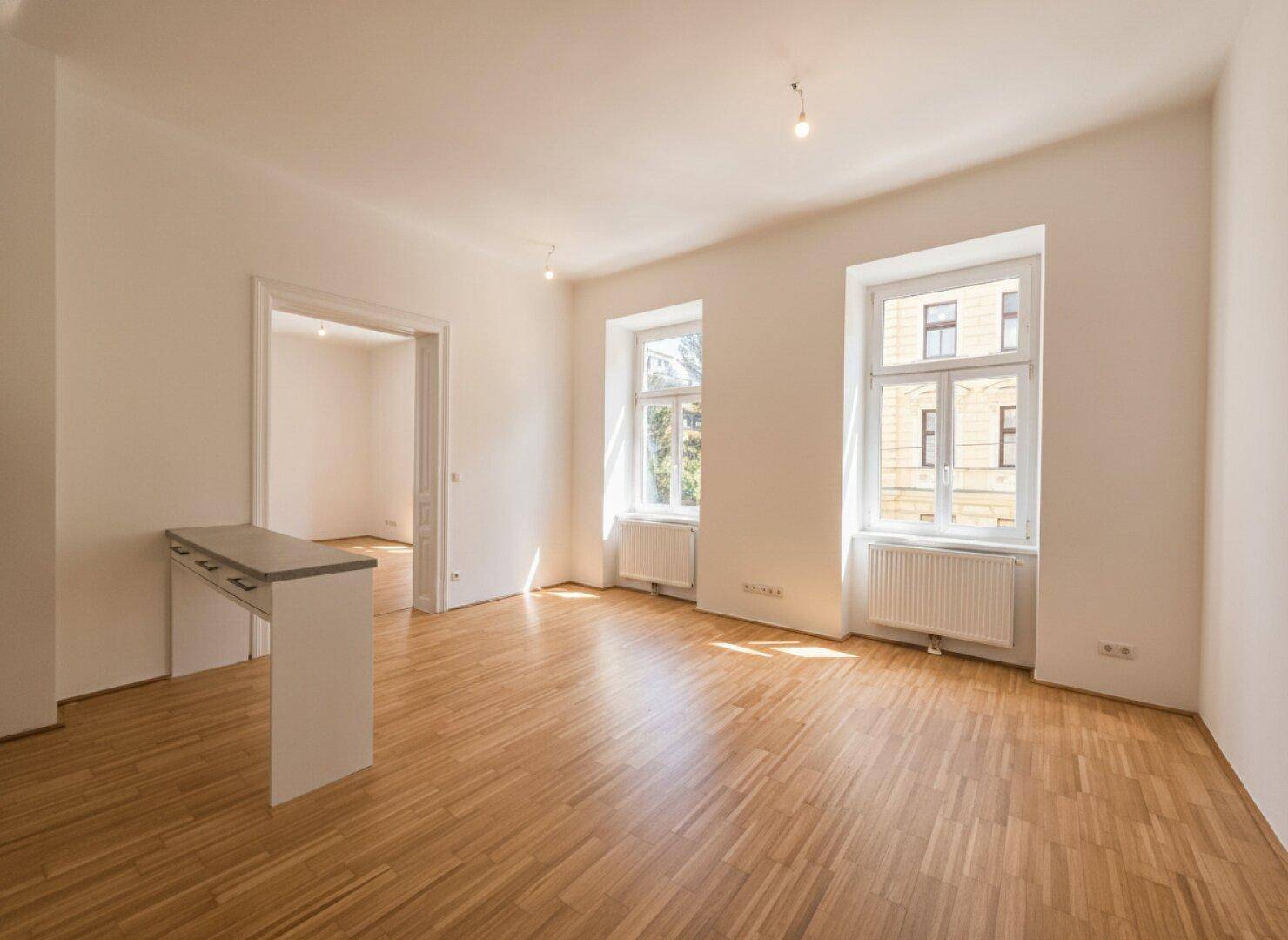 Geräumiger Wohnbereich mit Parkettboden und einer modernen Küchentheke, die den Raum strukturiert.