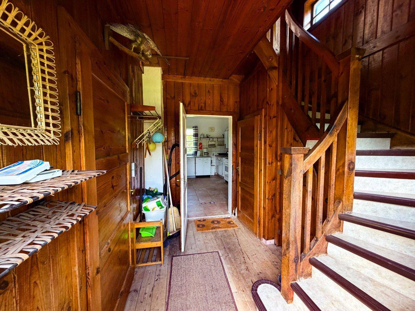 Rustikaler Flur mit Holzvertäfelung und Holztreppe, die zur oberen Etage führt.