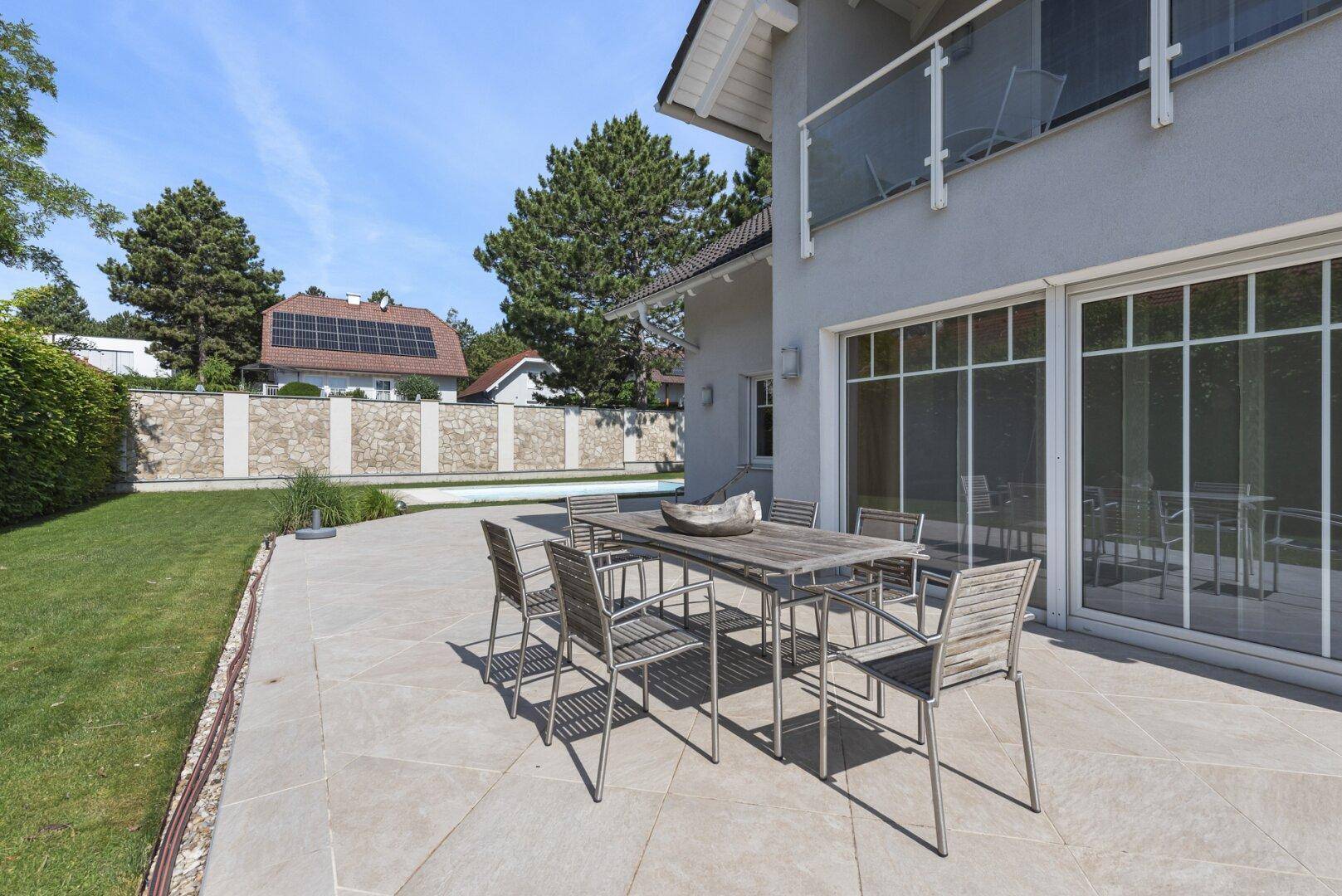 Große geflieste Terrasse mit Esstisch und Stühlen, ideal für Mahlzeiten im Freien.