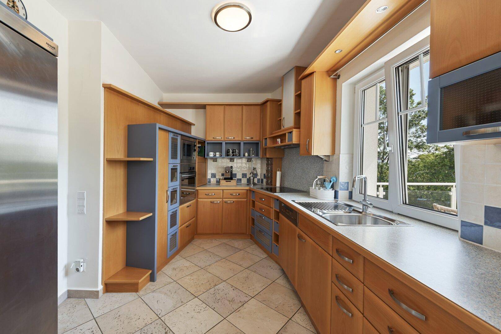 Geräumige Küche mit Holzschränken, blauen Akzenten und integrierten Geräten.