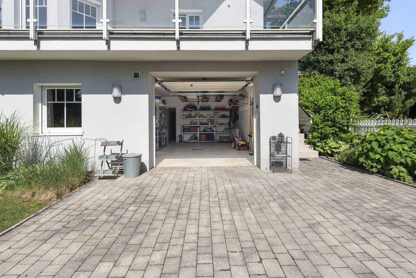 Einfahrt zur Doppelgarage mit gepflastertem Vorplatz und Zugang zum Haus.