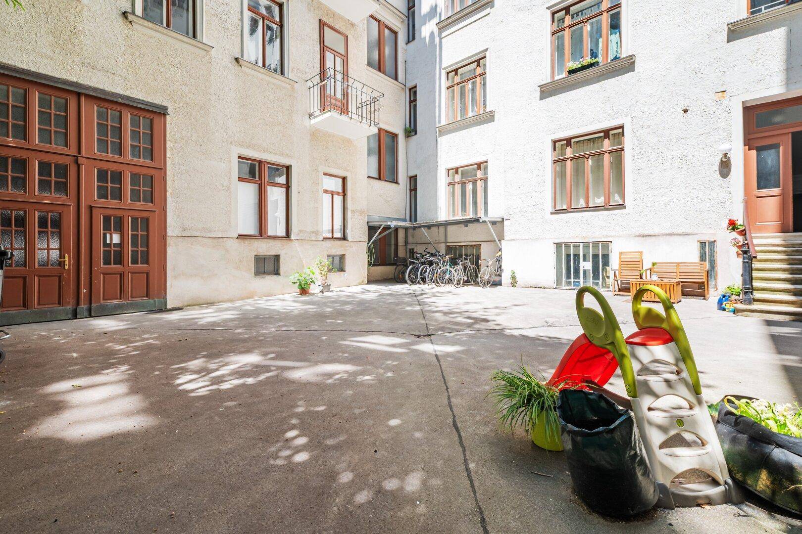 Heller Innenhof mit Fahrradabstellplatz und Kinderspielgeräten.