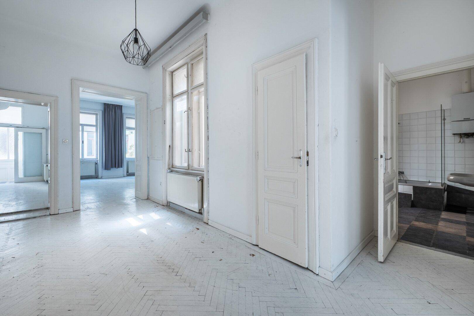 Geräumiger Flur mit Fischgrätparkett und Zugang zu verschiedenen Zimmern der Wohnung.