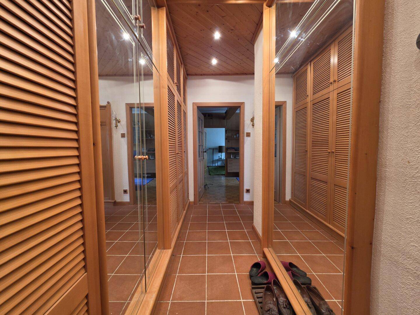 Flur mit Terrakottafliesen, Holzdecken und Spiegelschränken, die den Raum optisch vergrößern.