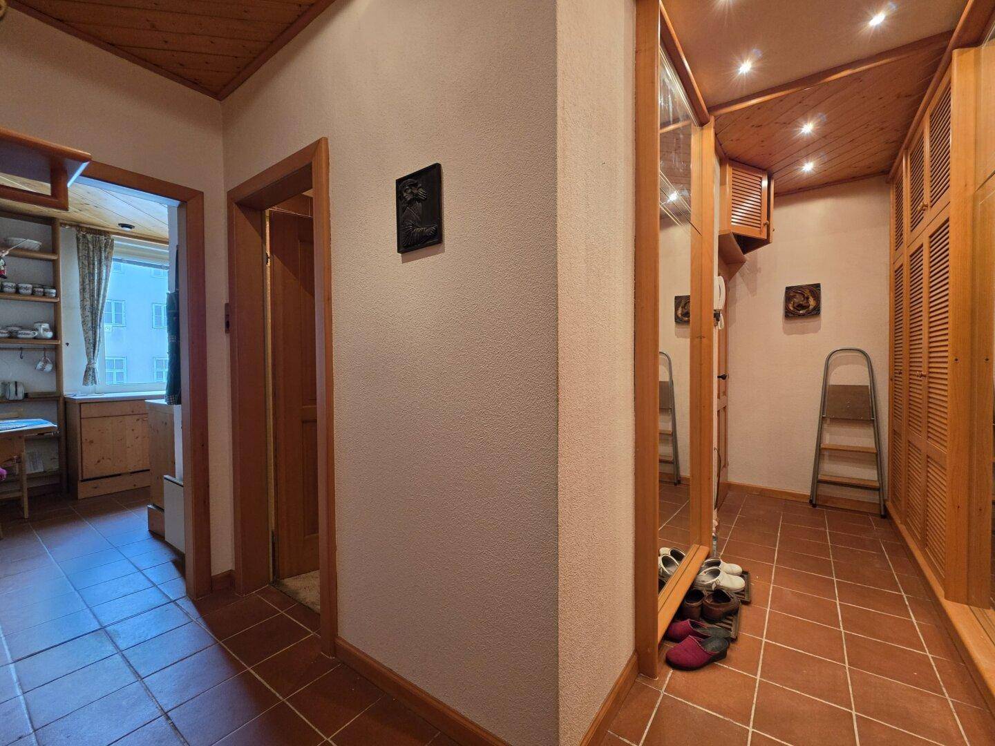 Heller Flur mit Terrakottafliesen, Holzdecken und integrierten Schränken, die praktischen Stauraum bieten.