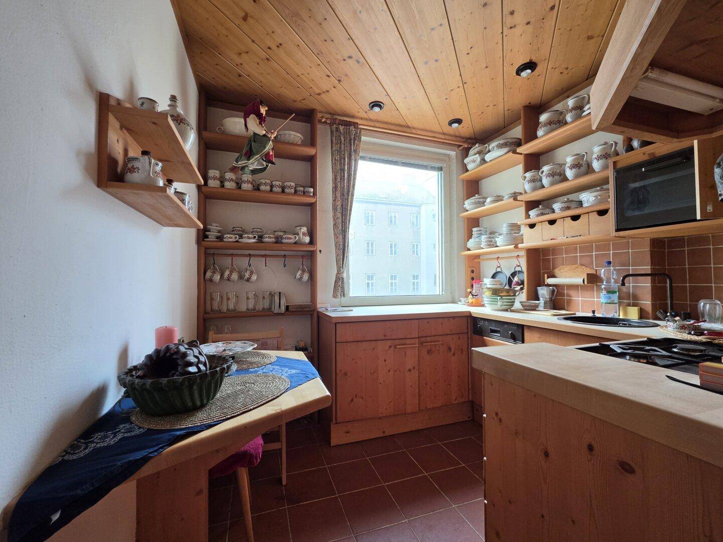 Rustikale Küche mit Holzdecken, Terrakottafliesen und offenen Regalen, die viel Stauraum bieten.