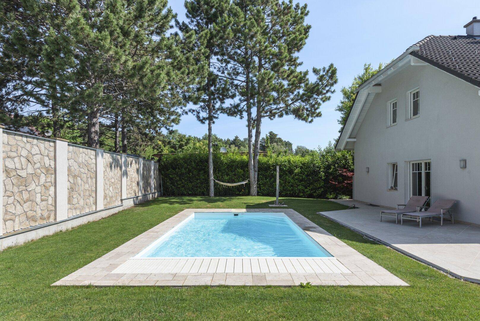 Großer Garten mit Pool, Rasenfläche und hohen Bäumen, ideal zur Entspannung.