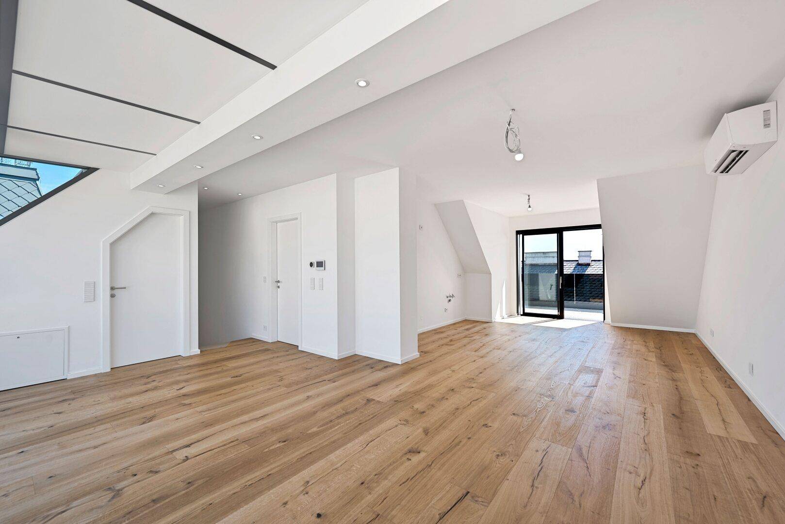 Heller Raum mit Holzboden, Klimaanlage und Zugang zu einer Terrasse.