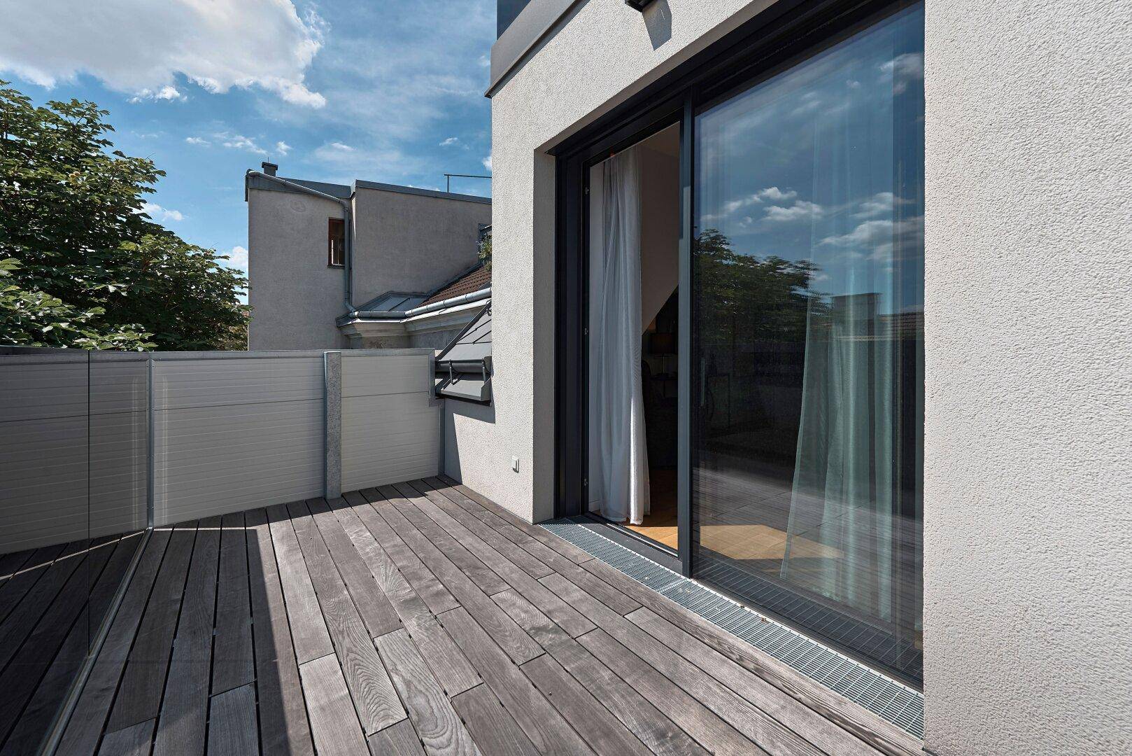 Helle Terrasse mit Holzboden und Schiebetür, ideal für entspannte Stunden im Freien.