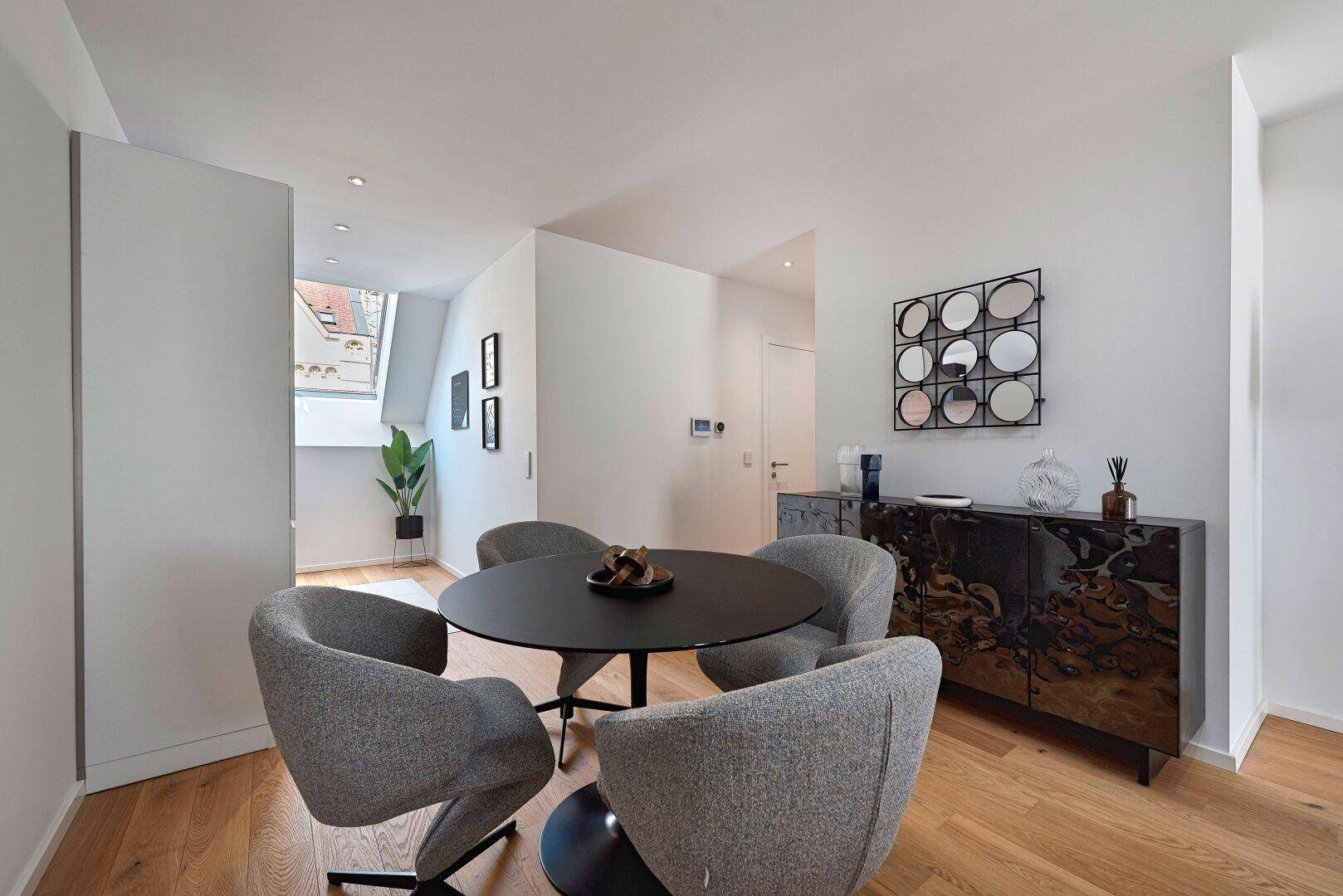 Eleganter Essbereich mit rundem Tisch und modernen Stühlen, ergänzt durch ein stilvolles Sideboard.