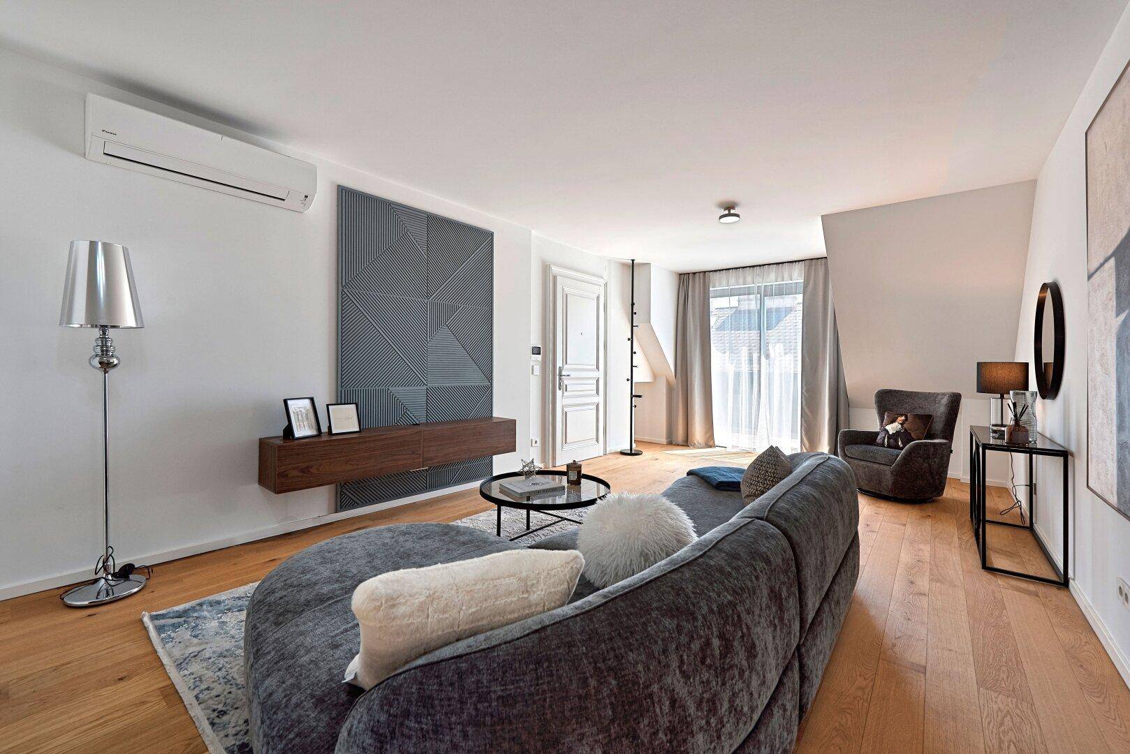 Modernes Wohnzimmer mit bequemer Couch, Holzboden und stilvoller Wanddekoration.