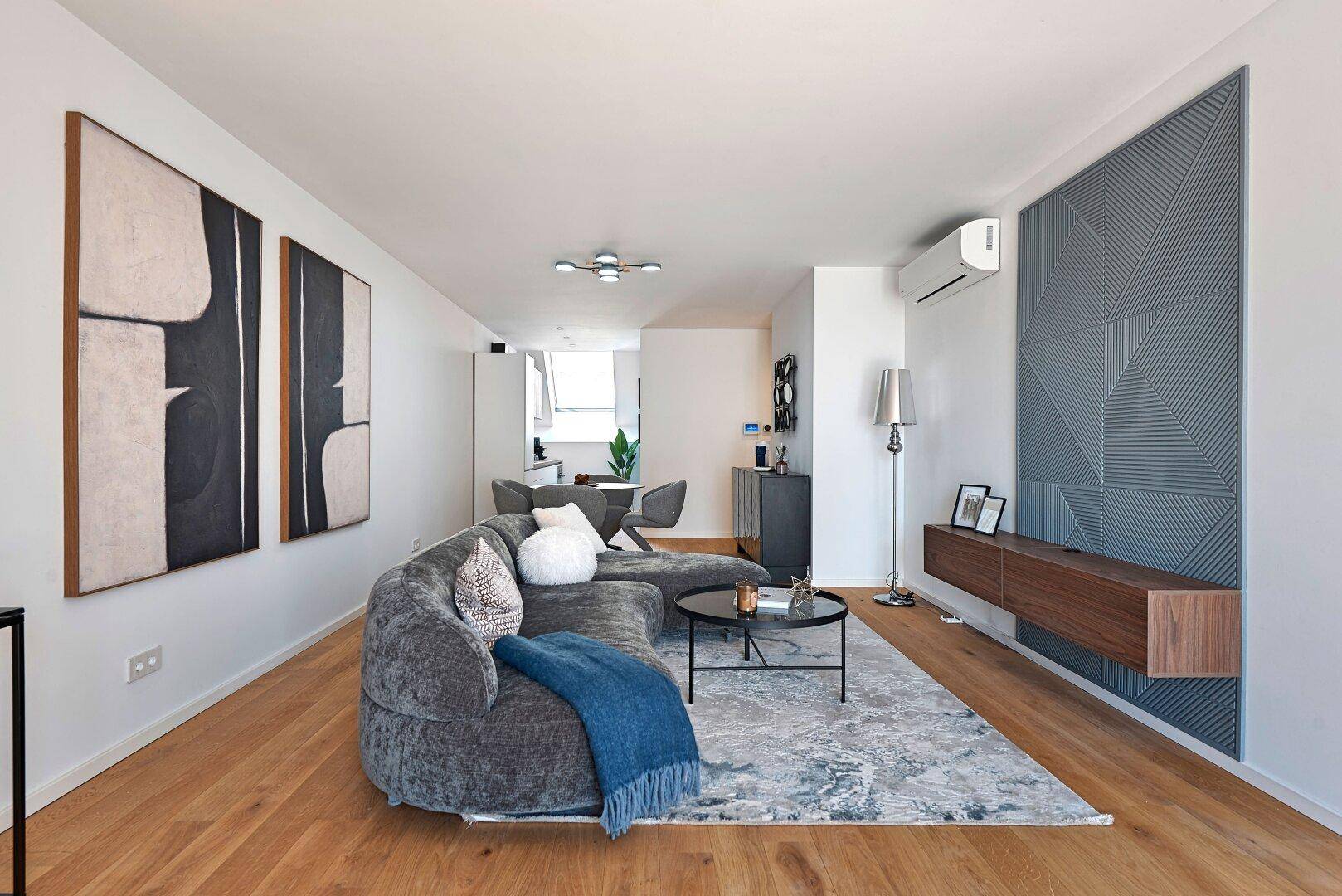 Offener Wohn- und Essbereich mit modernem Design, Holzboden und Kunstwerken an den Wänden.