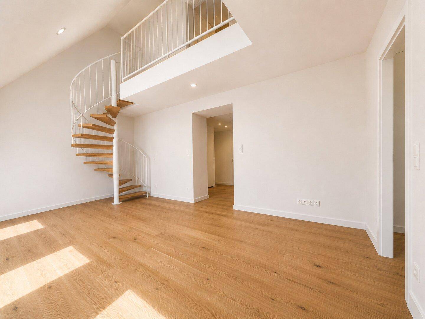 Geräumiger Raum mit Holzboden und einer eleganten Wendeltreppe, die zu einer oberen Galerie führt.