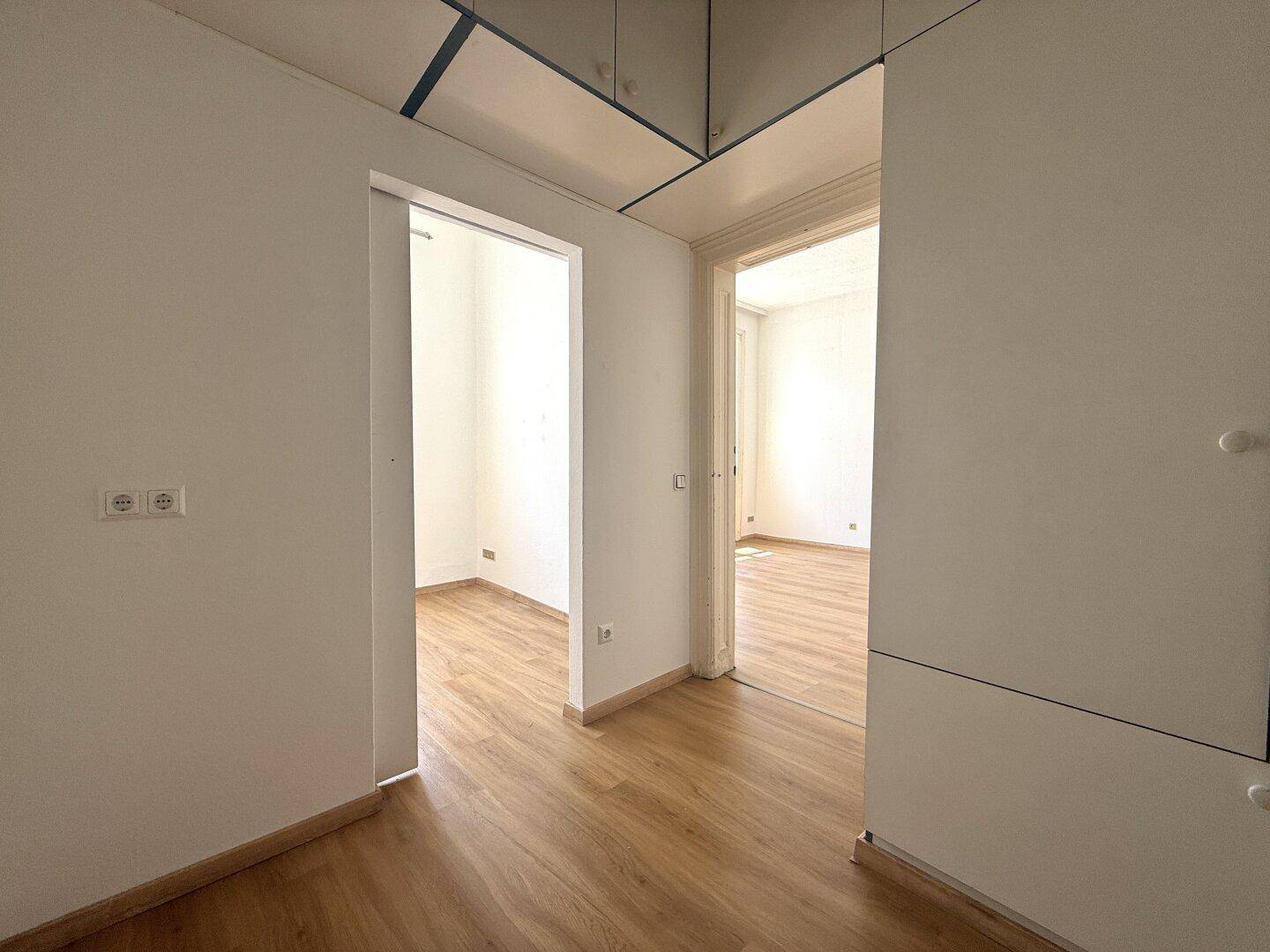 Heller Flur mit Holzboden und Durchgängen zu weiteren Zimmern, typisch für Altbauwohnungen.