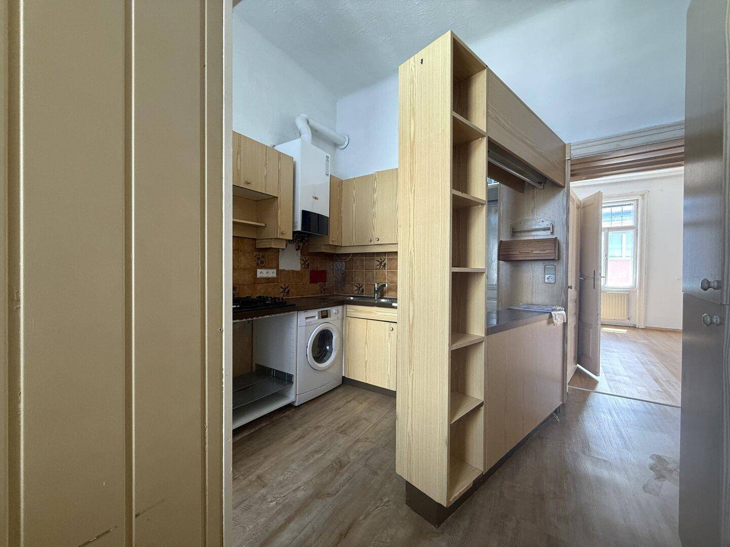 Funktionale Küche mit Holzschränken, Gasherd und Ofen, bereit zur Modernisierung.