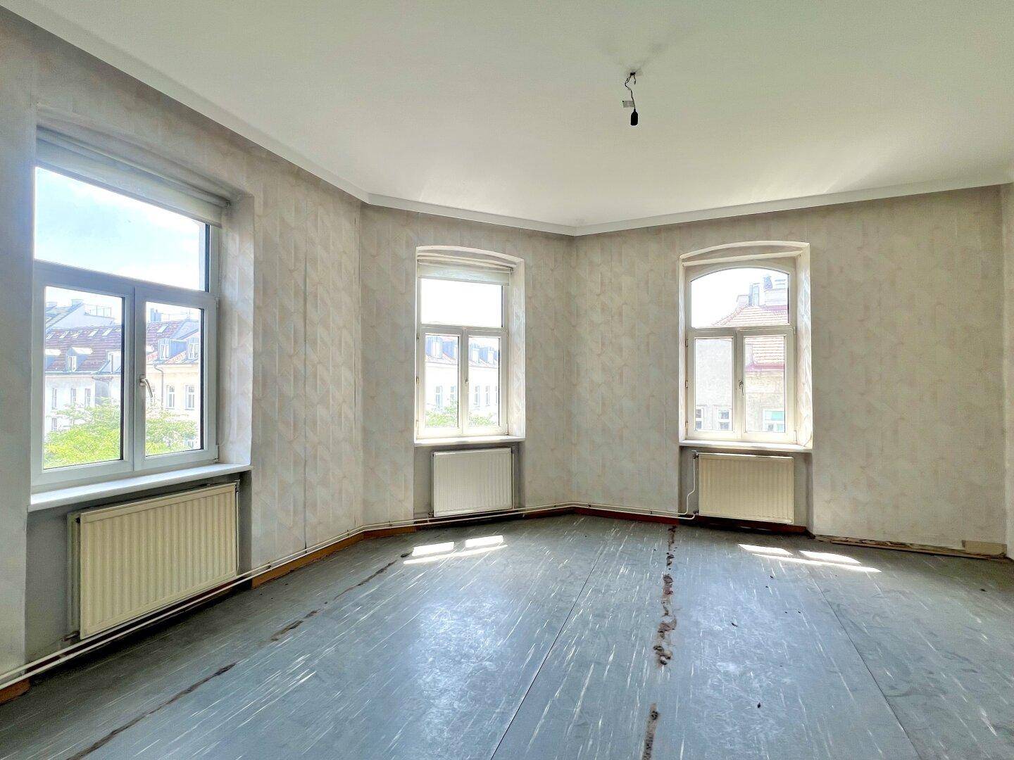 Heller, unmöblierter Raum mit drei großen Fenstern und Heizkörpern, ideal für individuelle Gestaltung.