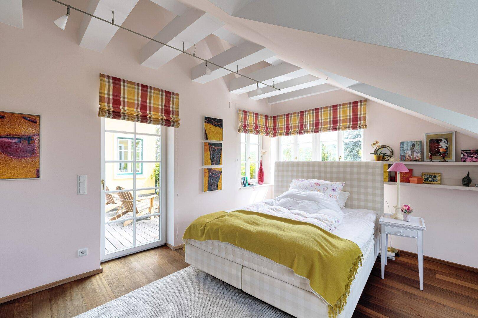 Helles Schlafzimmer mit Zugang zur Terrasse, Holzboden und sichtbaren Deckenbalken.