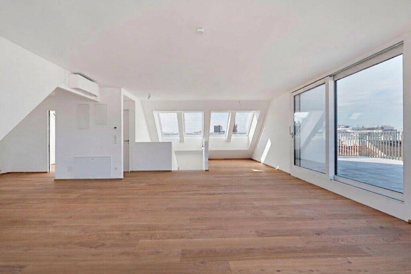 Heller, leerer Raum mit Holzboden, großen Schiebetüren und Zugang zur Terrasse.