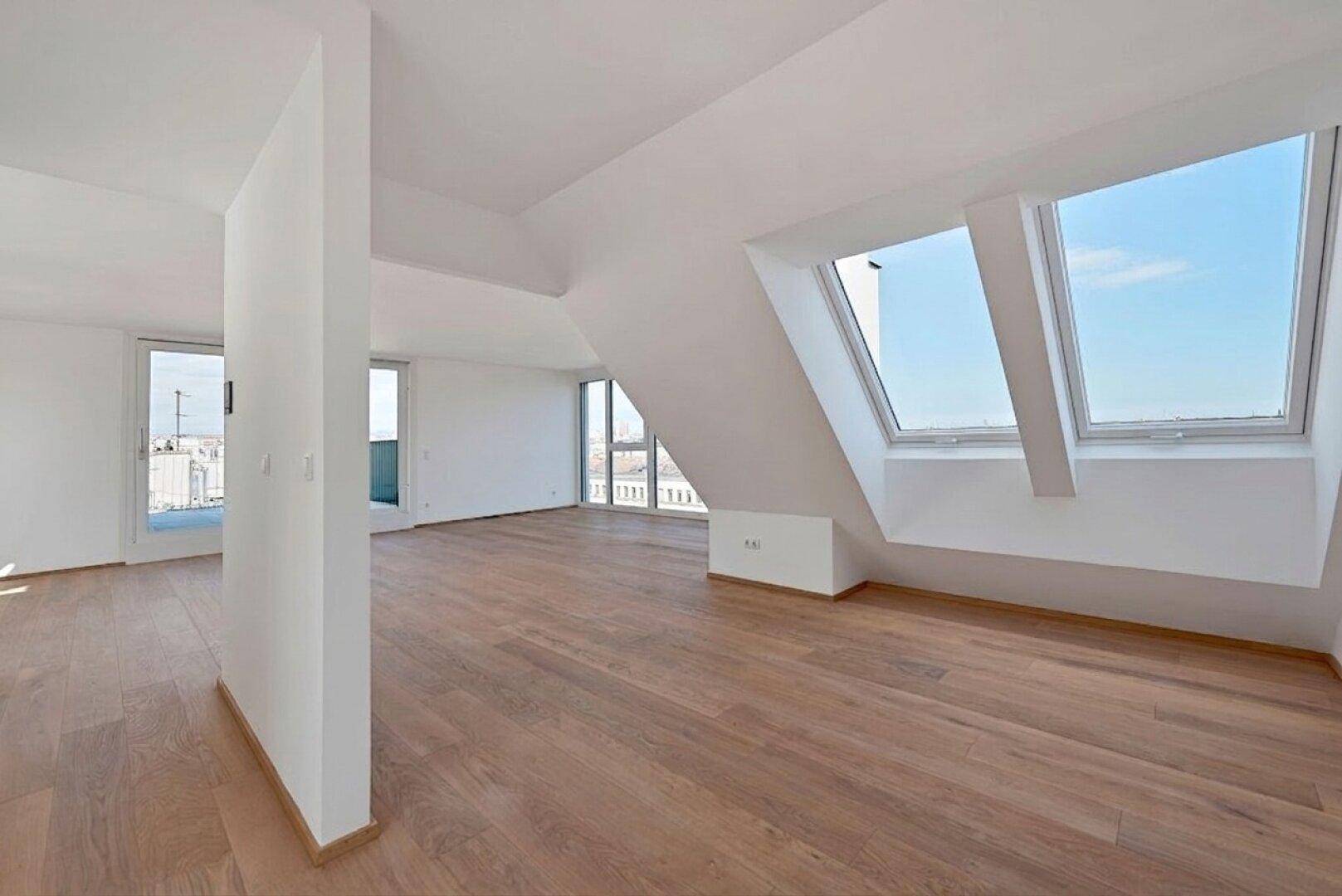 Offener Wohnbereich mit Holzboden, großen Fenstern und Zugang zur Terrasse.