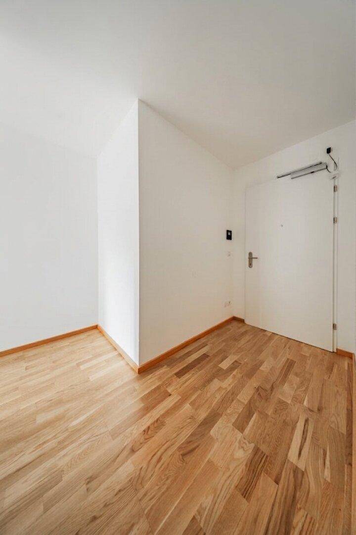 Heller Eingangsbereich mit Parkettboden und weißer Eingangstür, empfängt Bewohner und Gäste.