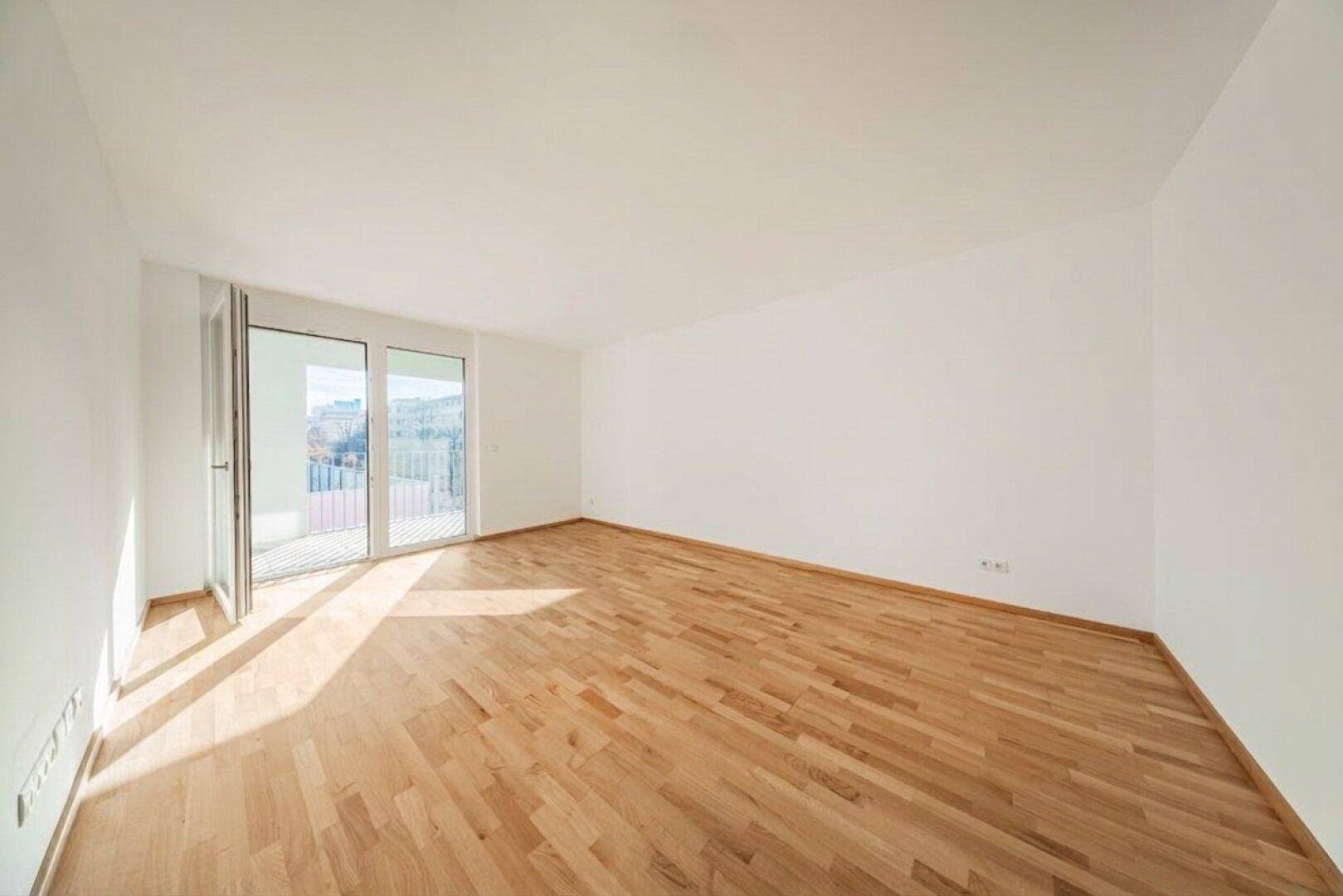 Geräumiger, unmöblierter Raum mit Holzboden und viel Tageslicht.
