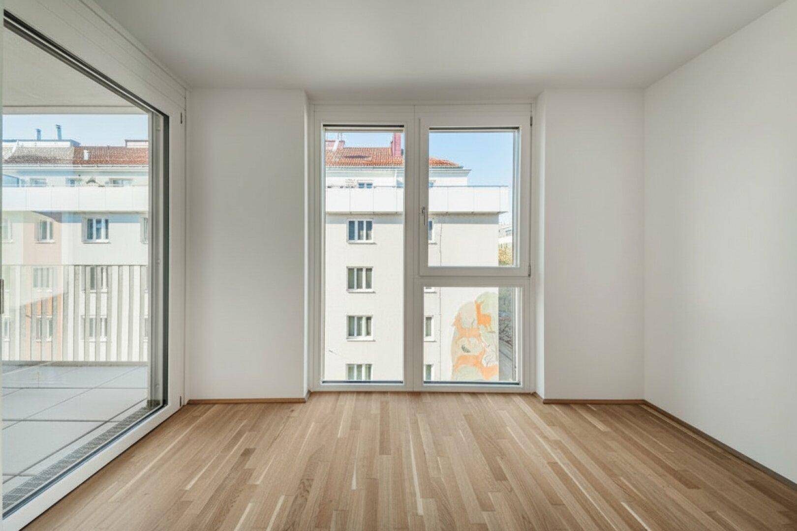 Heller Raum mit Parkettboden und großem Fenster, das viel Tageslicht hereinlässt.