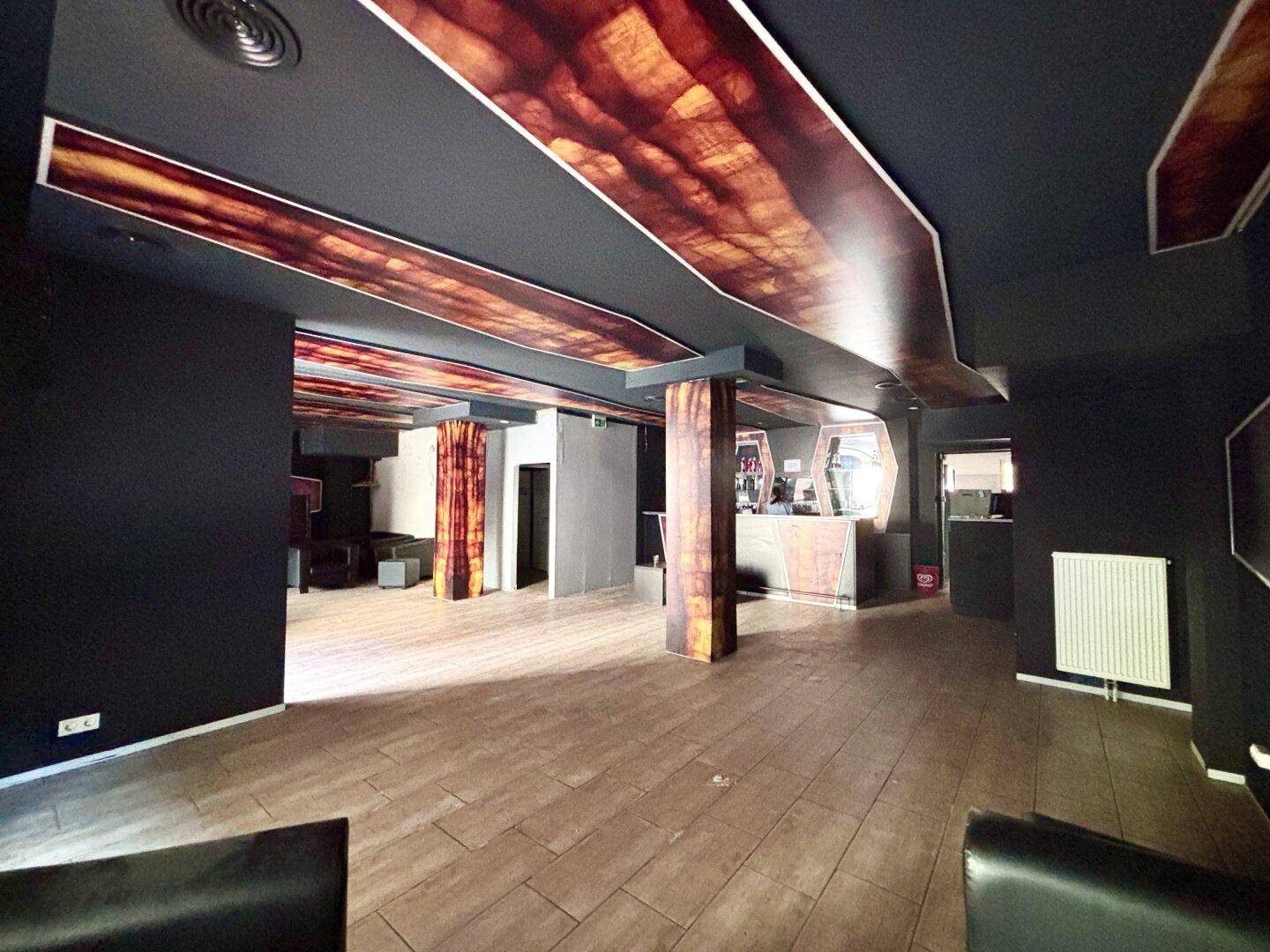 Geräumiger Gewerberaum mit Bar, dunklen Wänden, Fliesenboden und Heizkörper an der Wand.
