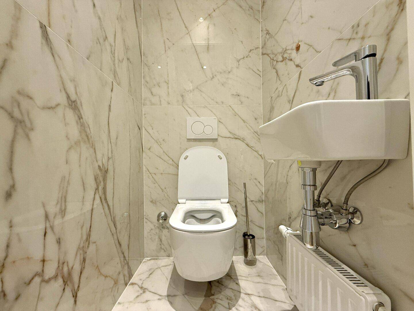 Elegantes Gäste-WC mit Marmorfliesen, wandhängendem WC und kleinem Waschbecken.