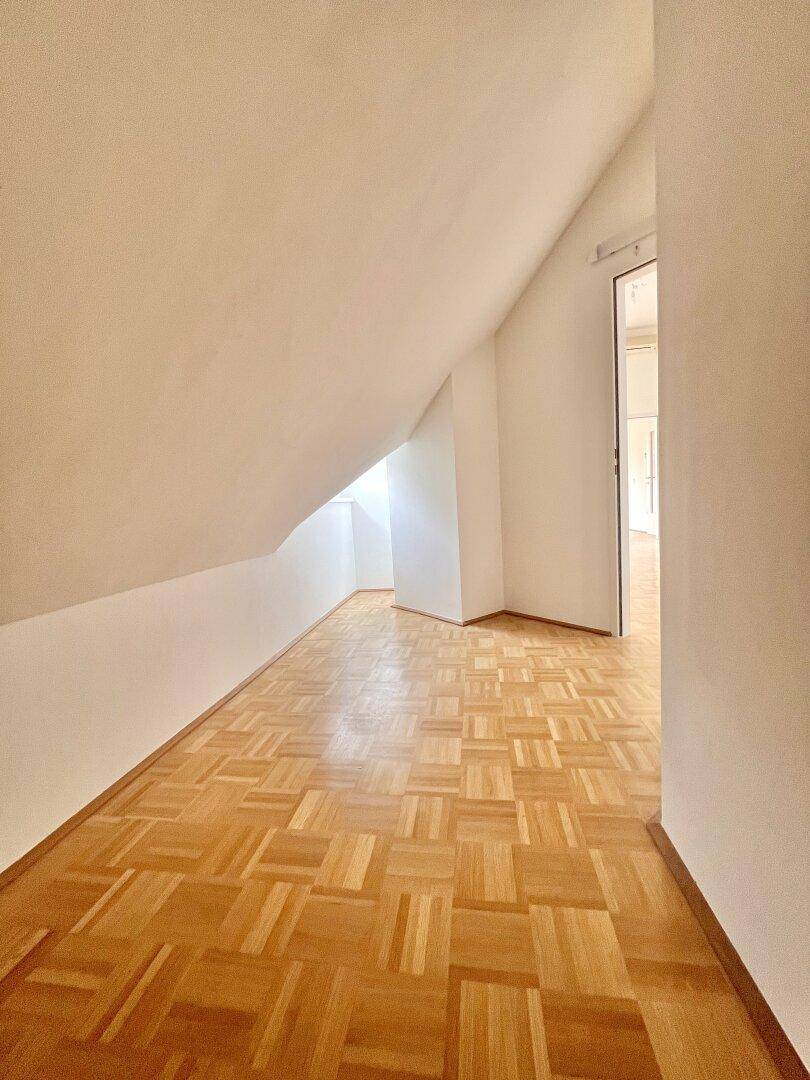 Heller Flur mit Parkettboden und Dachschrägen, der zu weiteren Räumen in der Dachgeschosswohnung führt.