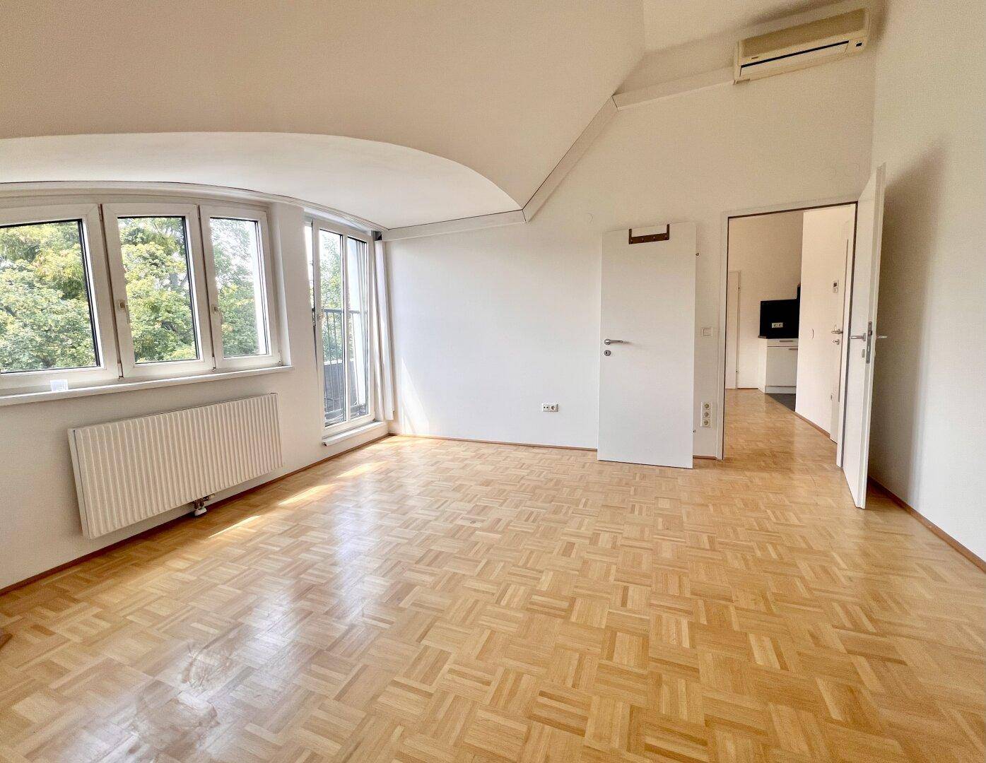 Heller Raum mit Parkettboden, Dachschrägen, französischem Balkon und Klimaanlage, der vielseitig nutzbar ist.