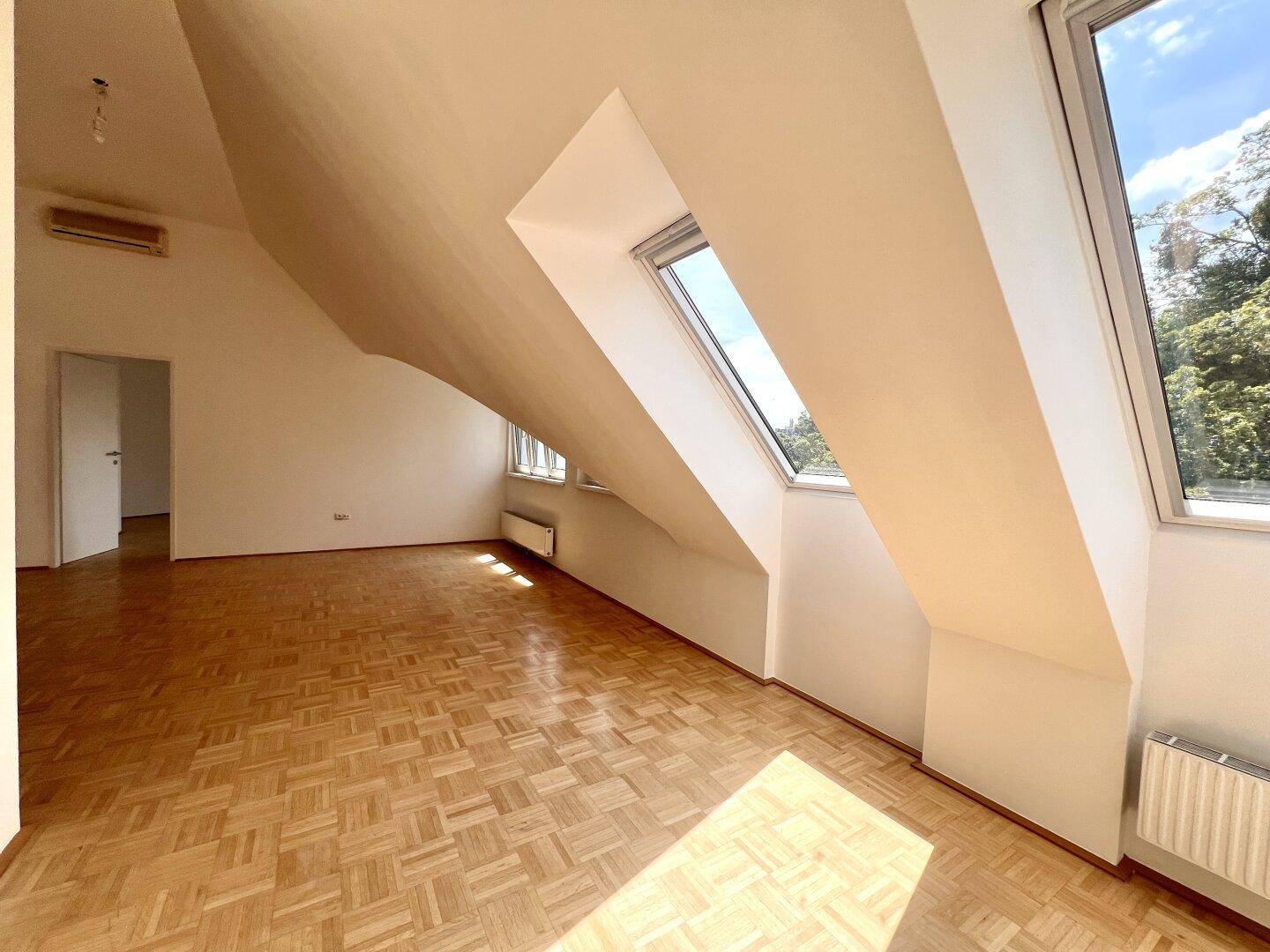 Geräumiges Dachgeschosszimmer mit Parkettboden, Dachfenstern und Klimaanlage, ideal für flexible Nutzung.
