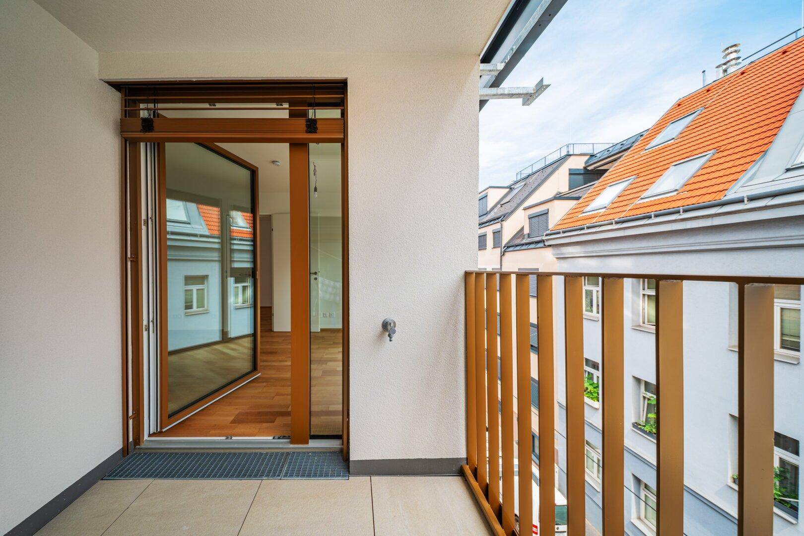 Heller Balkon mit Holzboden und Blick auf die umliegenden Dächer, ideal zum Entspannen.