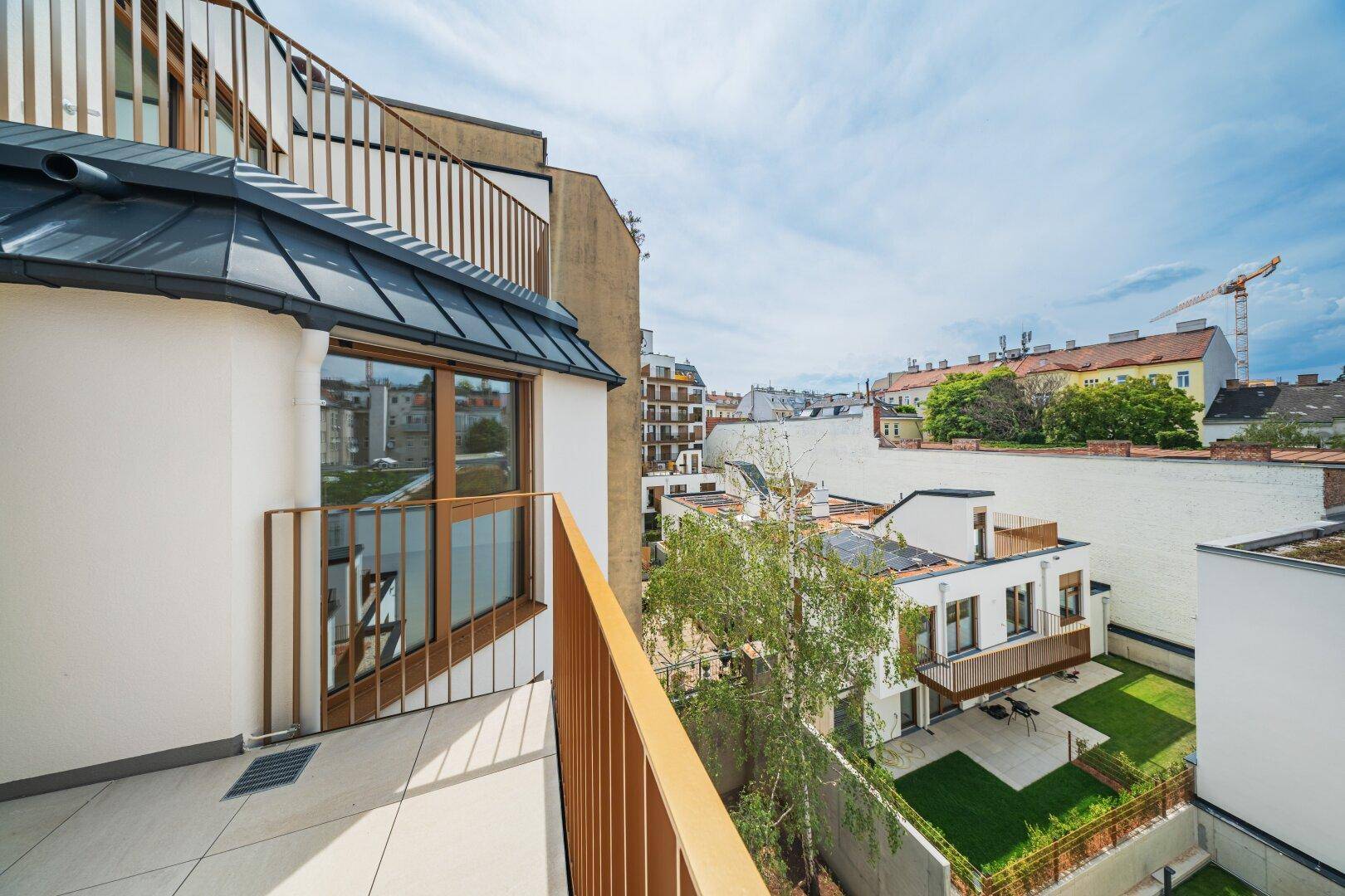 Geräumiger Balkon mit Metallgeländer und Blick auf die umliegende Stadt und Grünflächen.