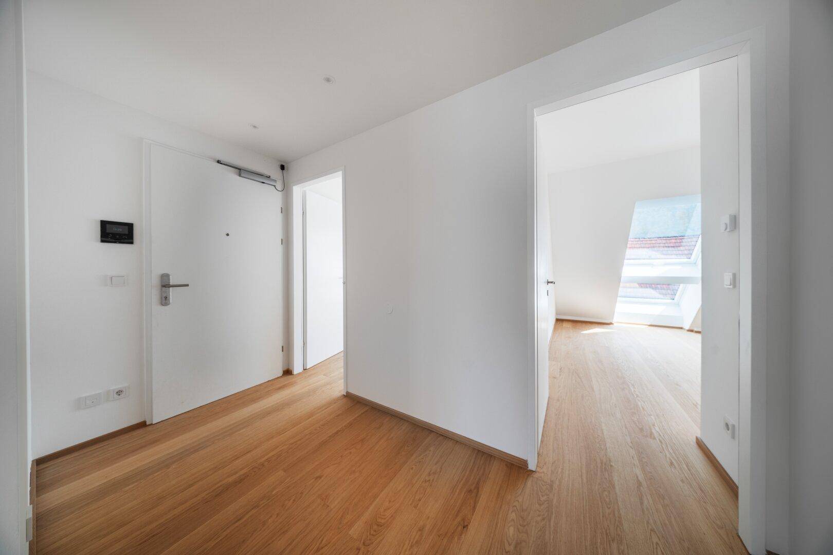 Heller Flur mit Holzboden und weißen Türen, führt zu weiteren Räumen der Wohnung.