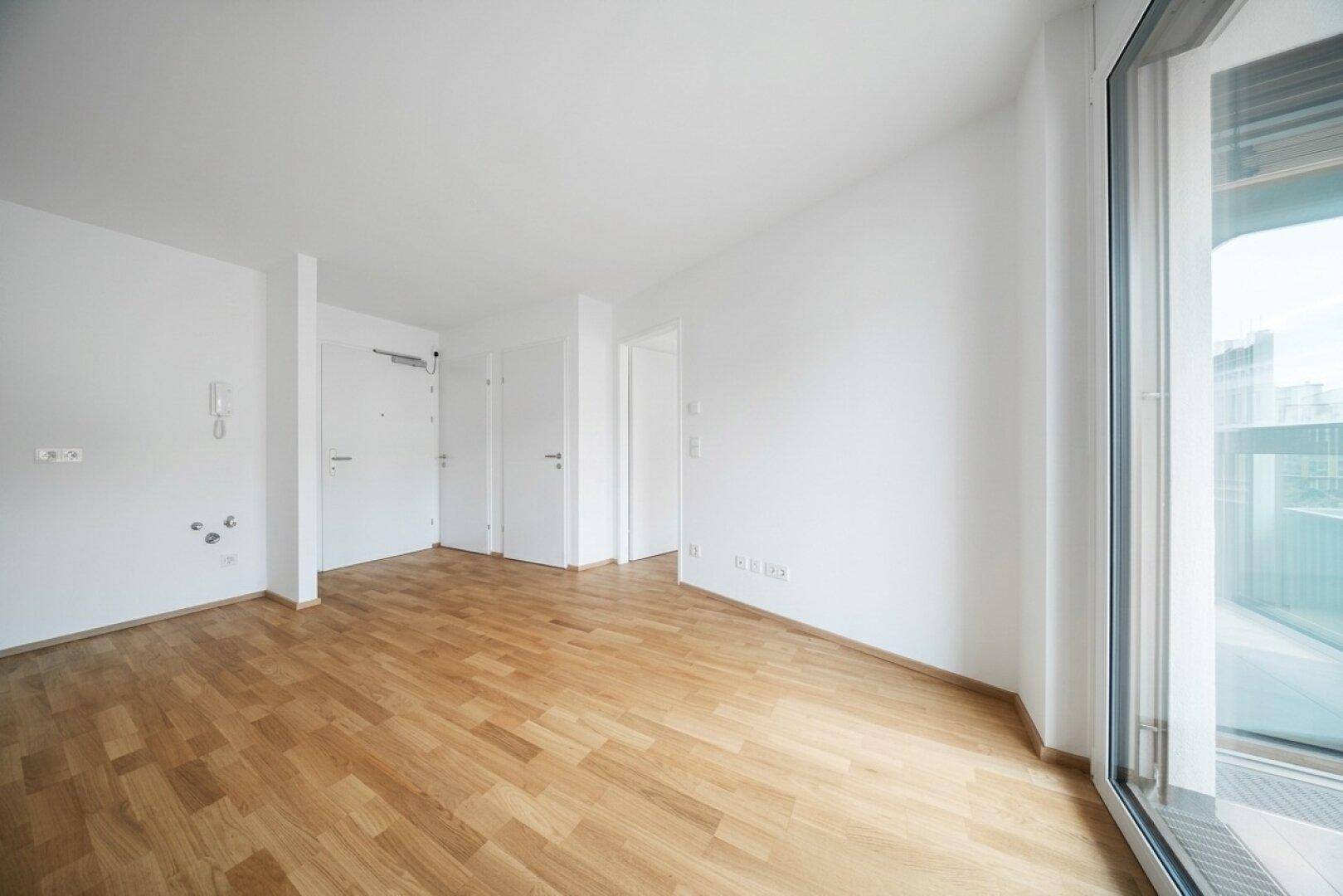 Heller Eingangsbereich mit Parkettboden und mehreren Türen zu angrenzenden Räumen.