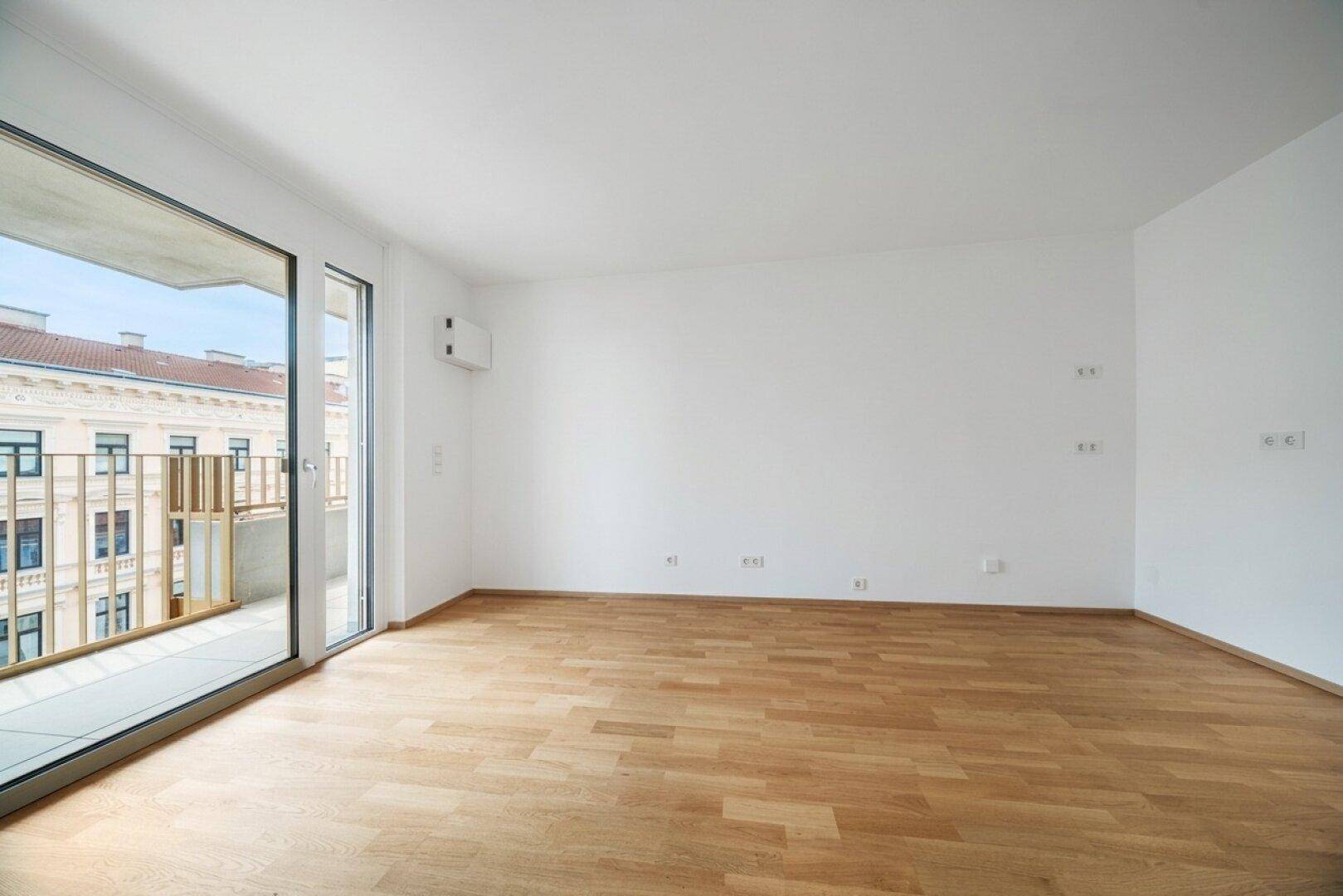 Heller Wohnraum mit Parkett und großem Fenster, das einen Blick auf die Stadt ermöglicht.