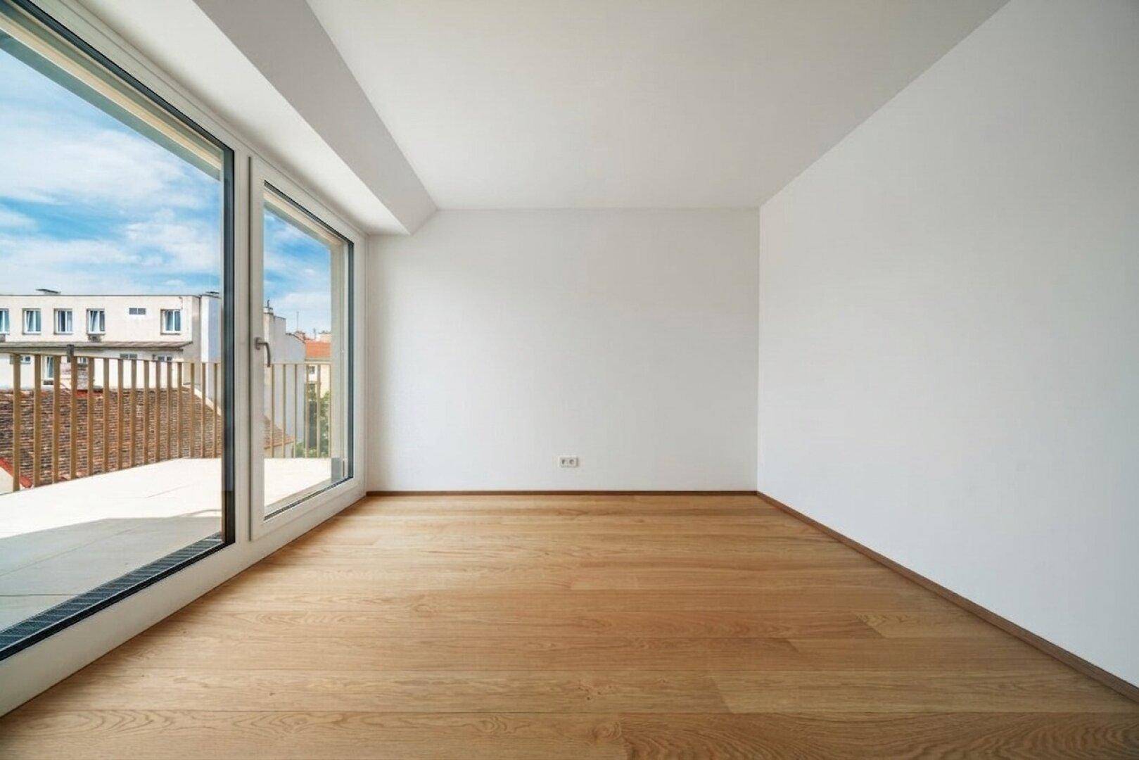Lichtdurchfluteter Raum mit Holzboden und großen Fenstern, ideal als Schlaf- oder Arbeitszimmer.