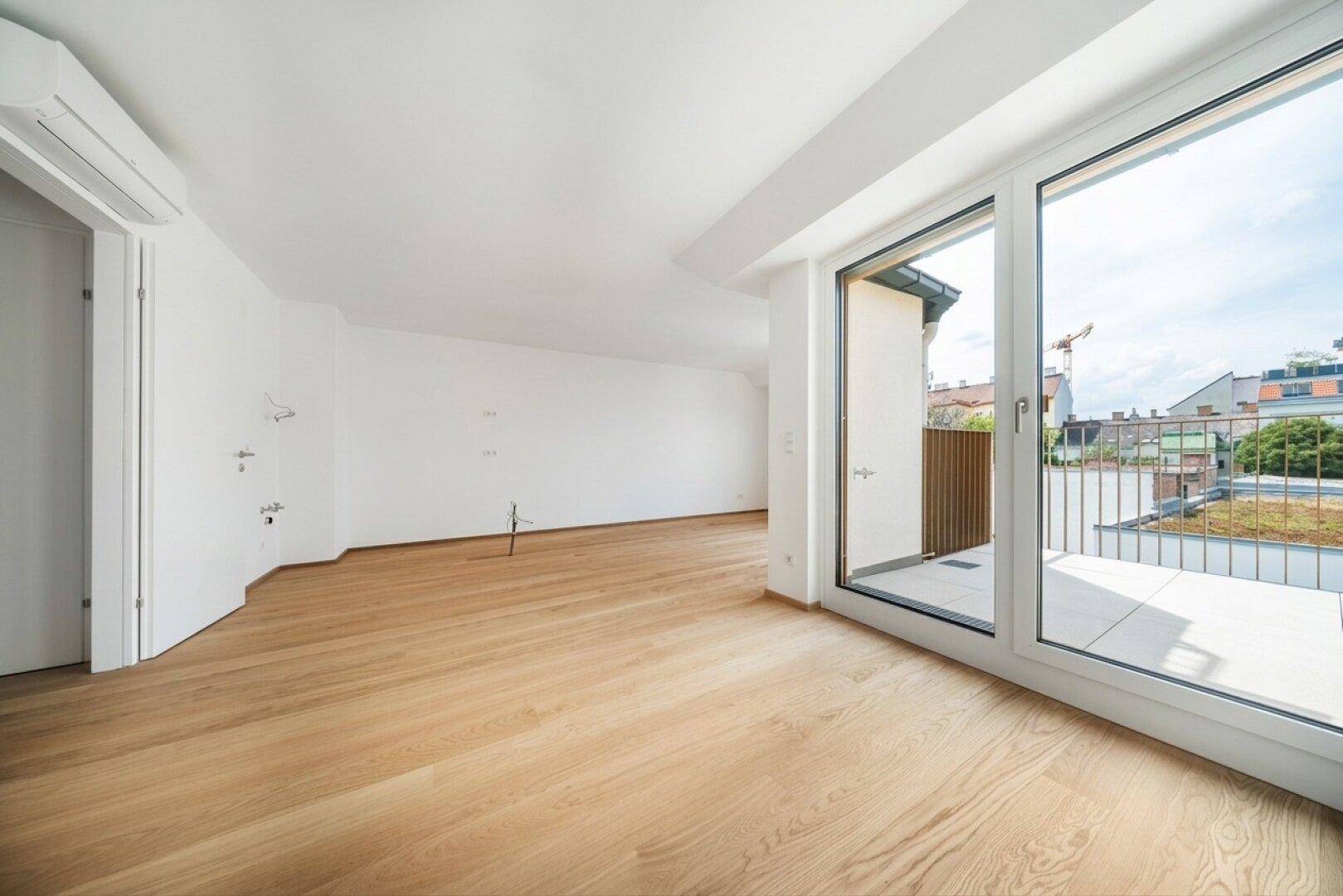 Geräumiges Zimmer mit Holzboden, Klimaanlage und Zugang zu einem sonnigen Balkon.