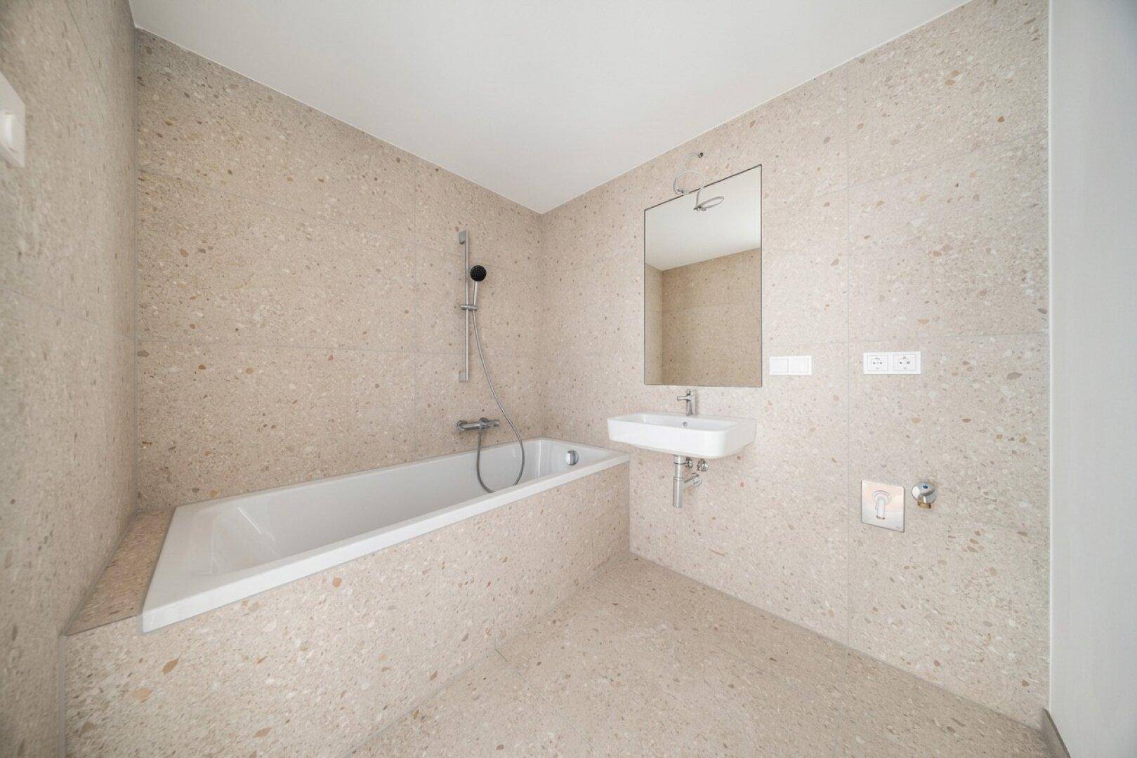 Modernes Badezimmer mit beigefarbenen Fliesen, Badewanne und Einzelwaschbecken.