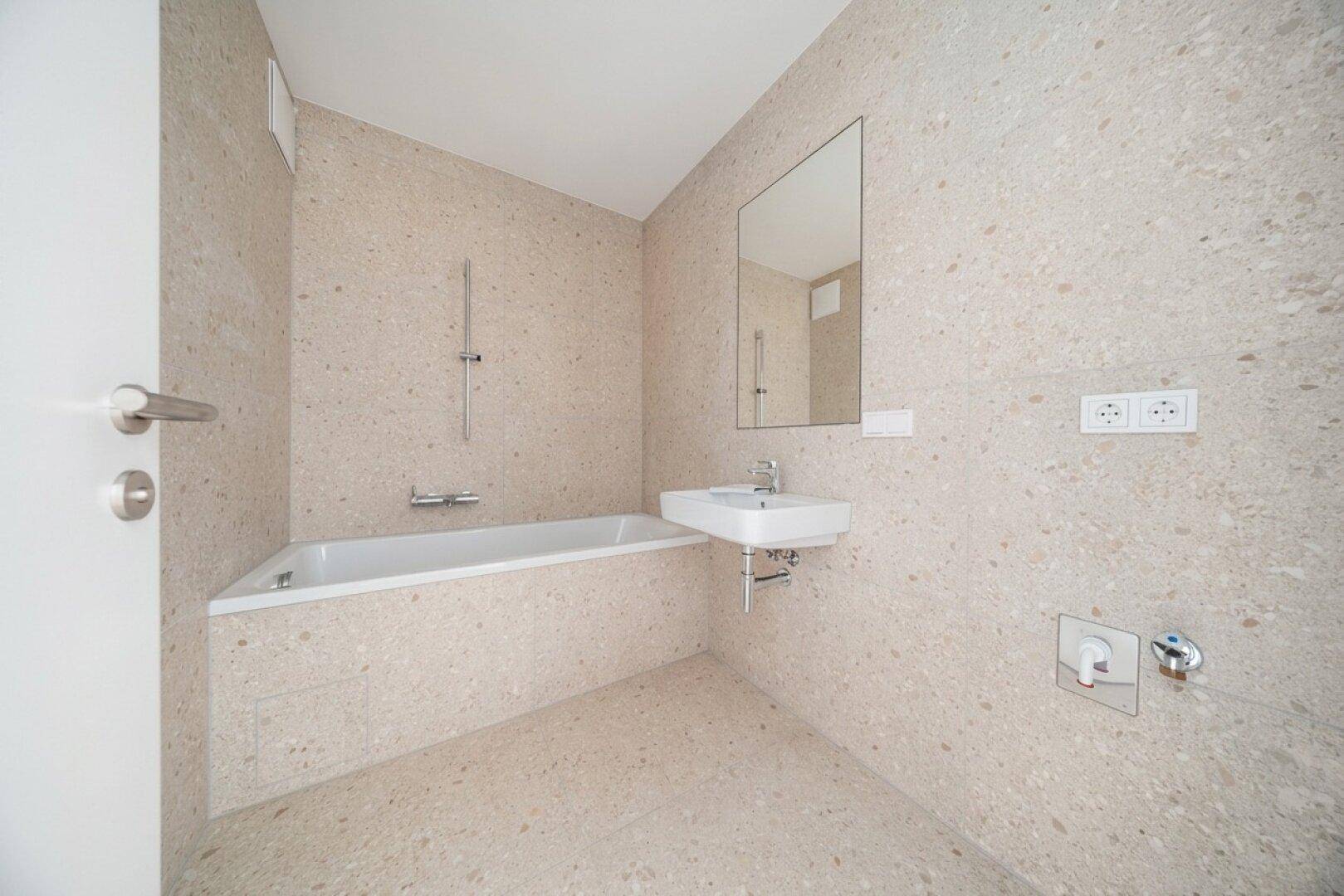 Modernes Badezimmer mit beigefarbenen Fliesen, integrierter Badewanne und Einzelwaschbecken.