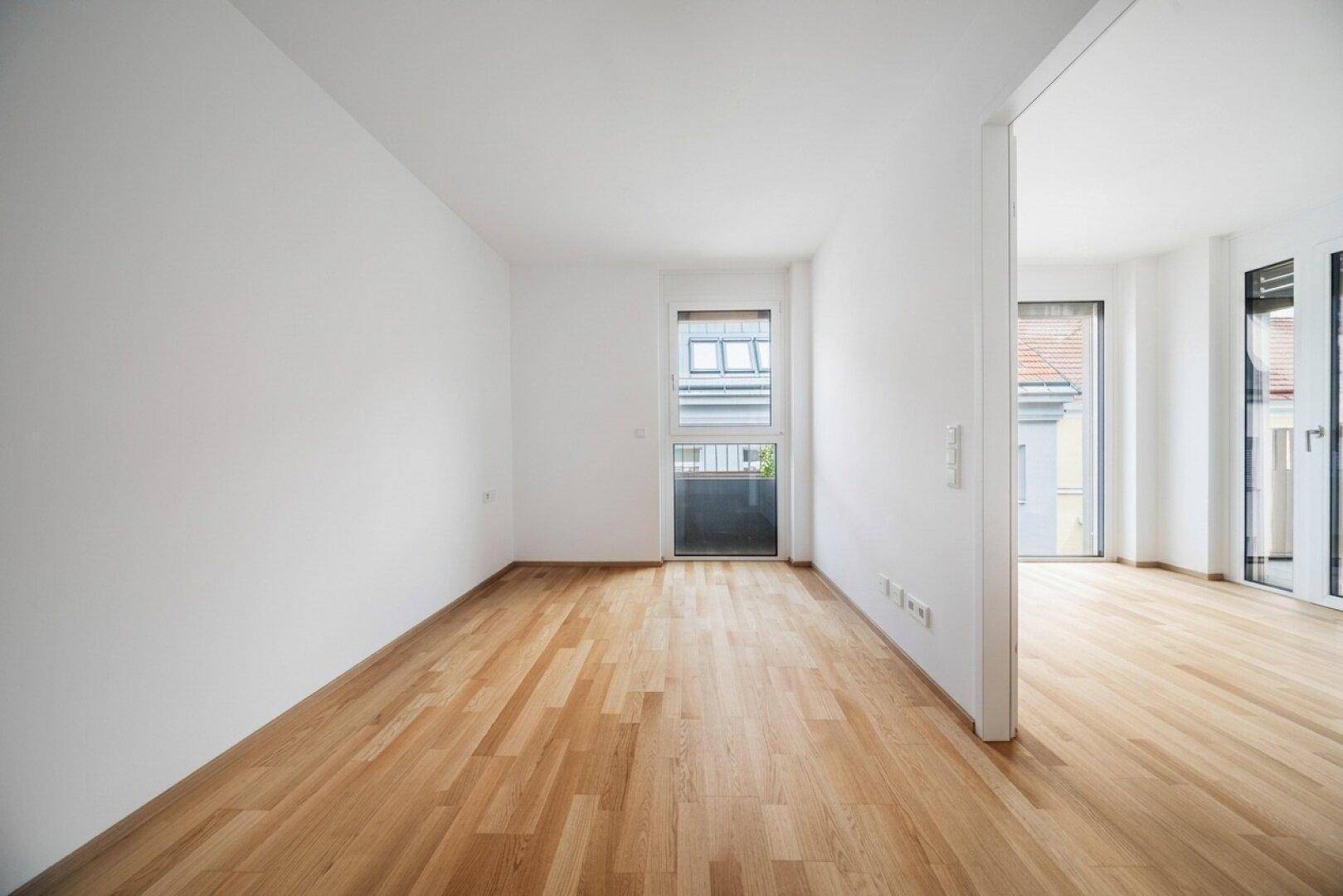 Heller, leerer Raum mit Parkettboden und mehreren Fenstern für eine angenehme Wohnatmosphäre.