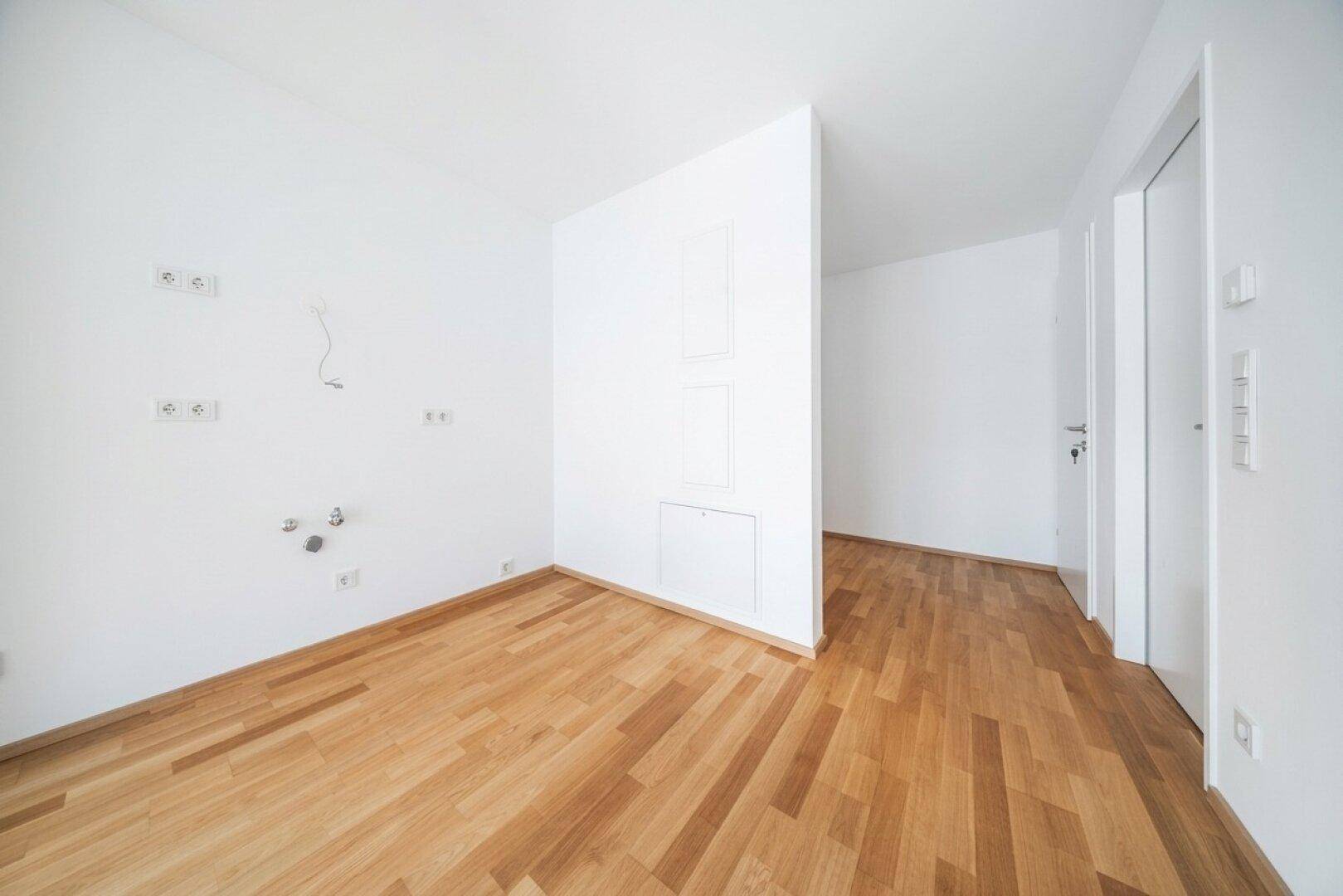 Leerer Raum mit Holzboden und weiß gestrichenen Wänden, bietet flexible Gestaltungsmöglichkeiten.