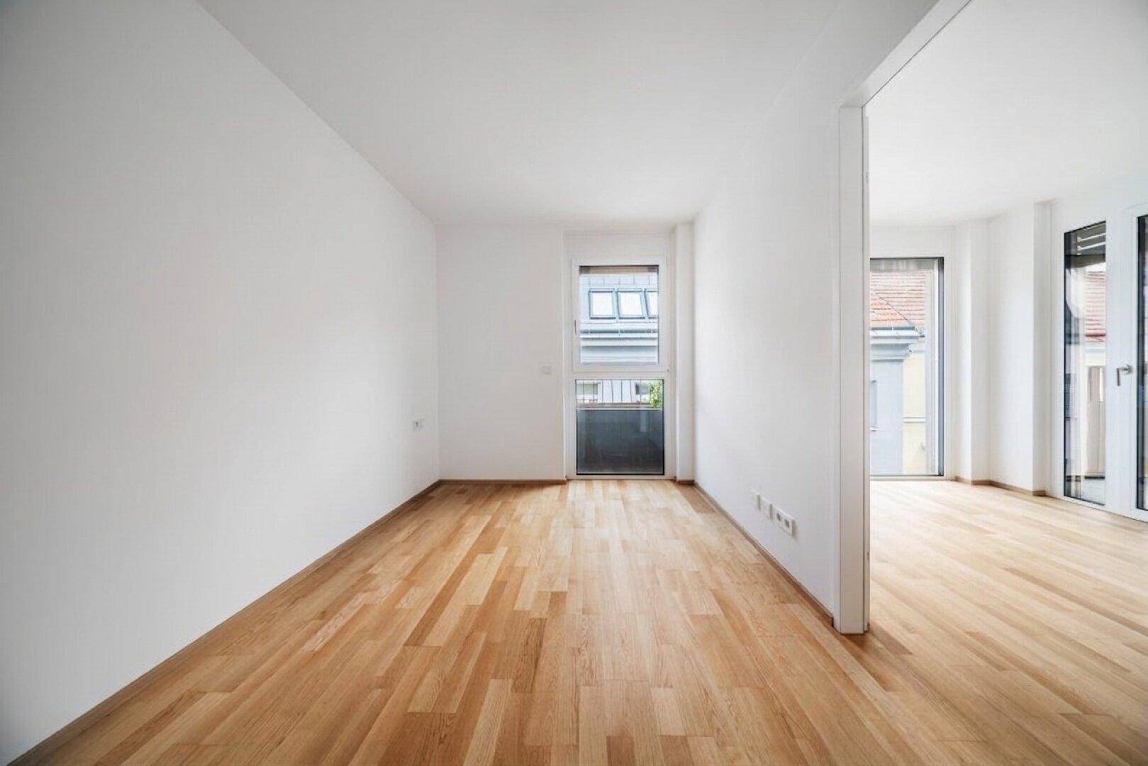 Helles Schlafzimmer mit Holzboden und Zugang zu einem kleinen Balkon, ideal für Ruhe.